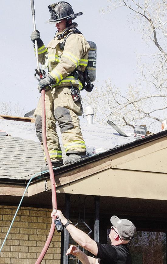 Clinton firefighter Bobby Winans, top, takes the hose from Interim Chief Mark Switzer, as they inspect a potential electrical fire Tuesday afternoon at 1725 W. Modelle Ave. CDN | Sam Goodwyn