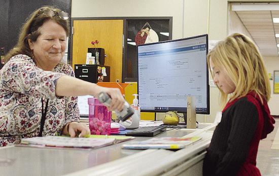 Nance Elementary School Librarian Sharon Harl, left, helps kindergartener Kezli Cox check out some new books Tuesday afternoon, on the first day of the new school semester. CDN | Micah Ashcraft