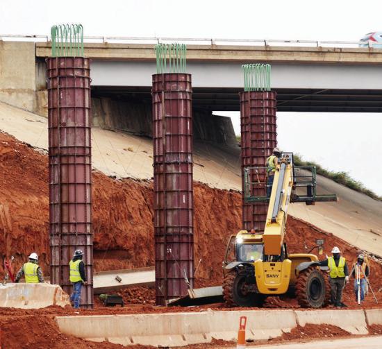 Construction crews install new support pillars for the Intestate 40 overpass Tuesday at Neptune Drive. CDN | Christian Jacobsen