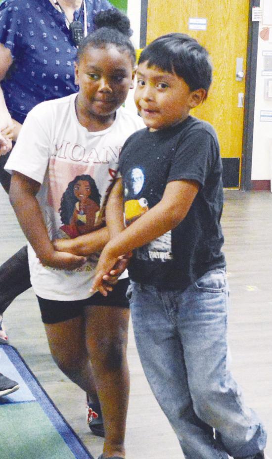 C’ianna Mbaneme, left, and James Bearshield promenade during their square dancing lesson at Nance Elementary. CDN | Christian Jacobsen