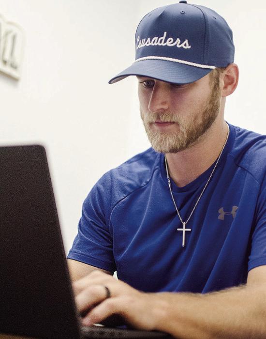 CDN | Sam Goodwyn New Corn Bible Academy football coach Peyton McNutt gets some work done Monday in his office.