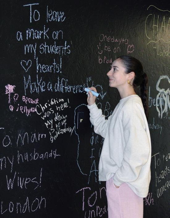 Miranda McLean adds positive notes to the wall of “The Spark Project” space on the corner of Frisco and Sixth Street. CDN | Christian Jacobsen