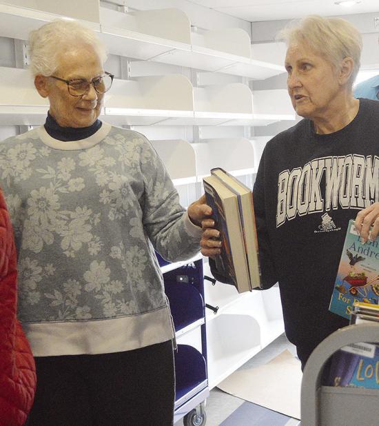 Western Plains Library System Board Members Carlotta England, left, and Kay Hagerman pass each other stacks of books while stocking the shelves of the new WPLS bookmobile. CDN | Micah Ashcraft Western Plains Library System Board Members Carlotta England, left, and Kay Hagerman pass each other stacks of books while stocking the shelves of the new WPLS bookmobile. CDN | Micah Ashcraft