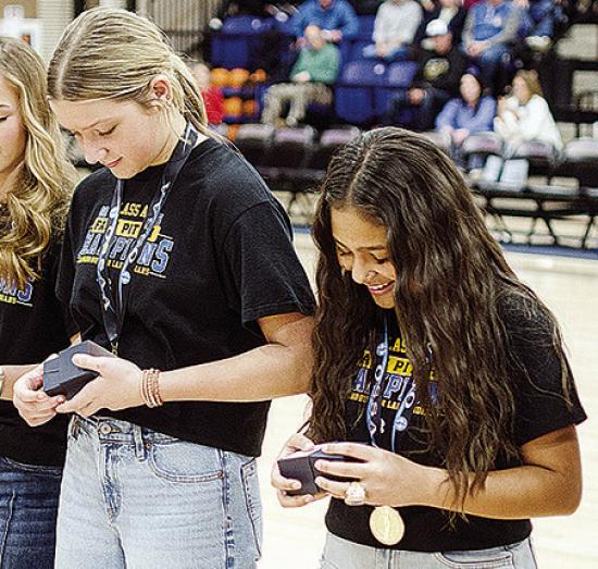 Lyla Pruitt, left, and Adrian Randle open their state championship ring boxes during halftime of the Arapaho-Butler boys’ basketball game Tuesday at home. CDN | Sam Goodwyn