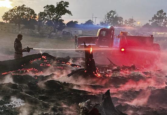 Clinton Fire Department Firefighter Alex Tyler attempts to extinguish remaining embers Saturday at the Commerce Industrial Center, east of Clinton Cemetery. CDN | Courtesy photo