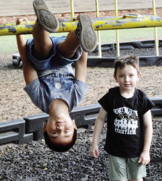Gabriel Gonzalez wanted to hang upside down while Jimi Haag jumped into the photo Friday at Nance Elementary. CDN | Christian Jacobsen