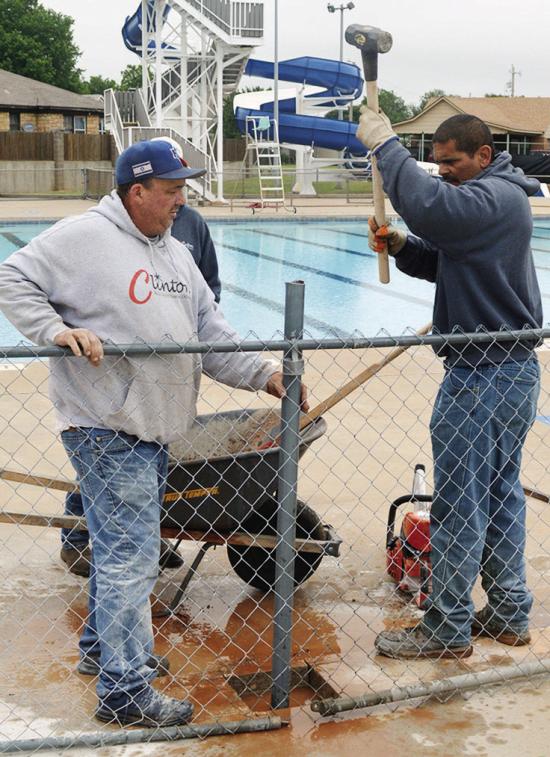 David Russell, left, and Robert Plaza replace and install a new fence post at the Clinton Swimming Pool. CDN | Christian Jacobsen