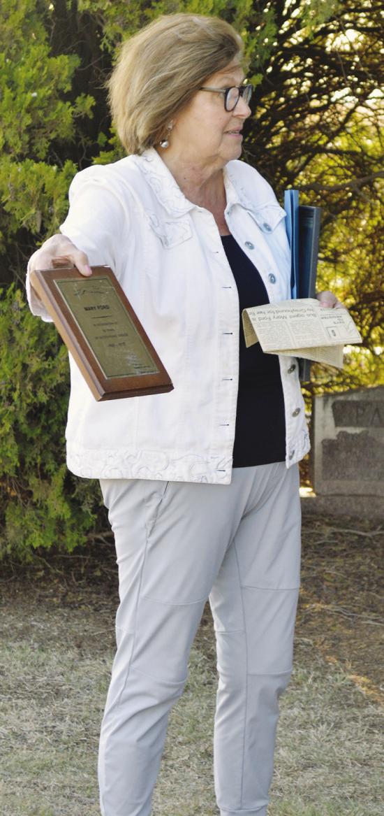 Linda Ford displays the awarded plaque of Mary Ford recognizing 50 years of service to the Greyhound Bus line for the 2026 Spring Cemetery Walk at the Clinton Cemetery. CDN | Christian Jacobsen