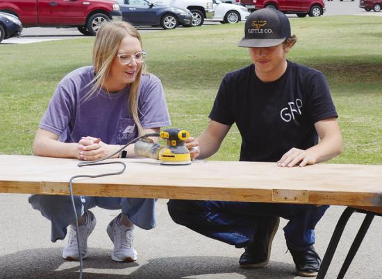 Alexia Newman guides Sy Foster while he sands a wooden door at Clinton High School. CDN | Christian Jacobsen
