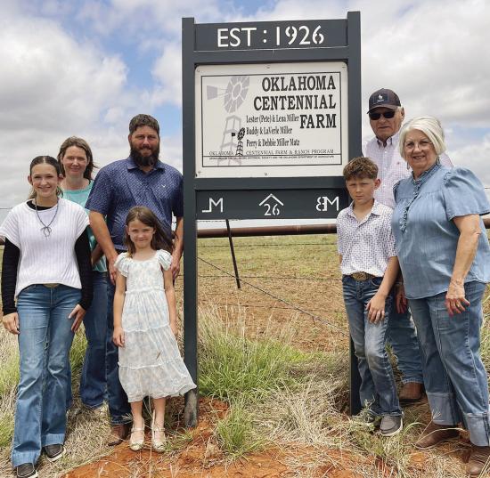 The Matz family, consisting of, from left, Kendall, Kyla, Kimber, Derek, Kellan, Perry, and Debbie Matz pose with the sign designating the Miller/Matz Farm as a historical landmark near Arapaho. CDN | Courtesy photo