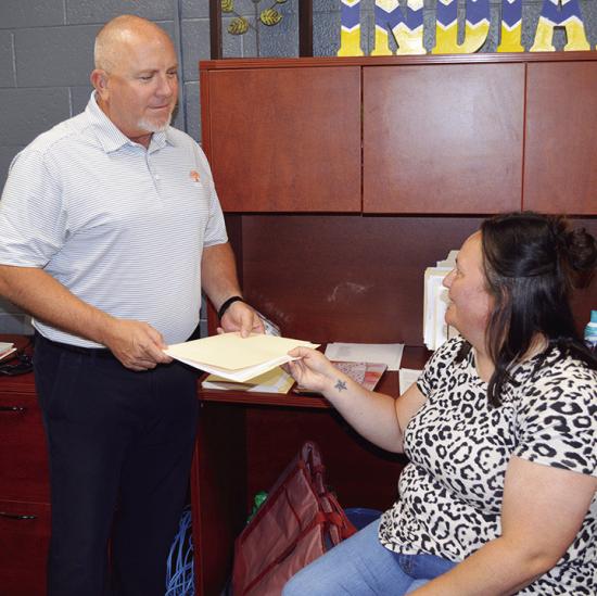 Brad Southall, left, receives papers from McKinsey Cloninger at Arapaho-Butler Elementary School. Cloninger will be the school’s new elementary secretary and child nutrition clerk in the 2026-2027 school year. CDN | Christian Jacobsen