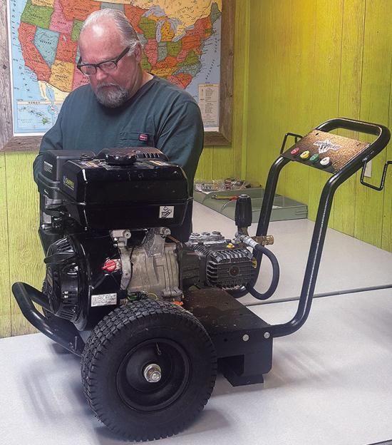 Rick Walker preps a pressure washer at Ranch Work Equipment for display at the Oklahoma City Farm Show. CDN | Christian Jacobsen