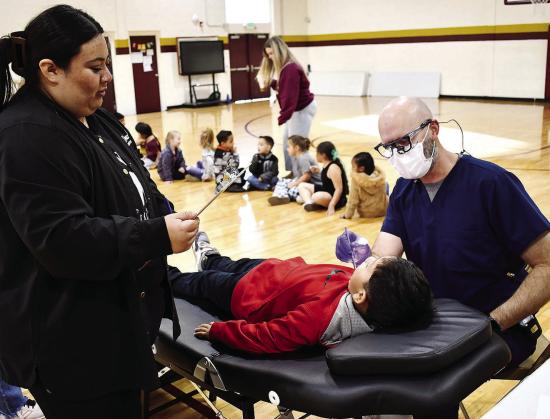 Joanna Martinez, WTC dental assisting student, left, records Dr. Kyle Serfoss’ findings while examining Alejandro Quezada recently at Nance Elementary.