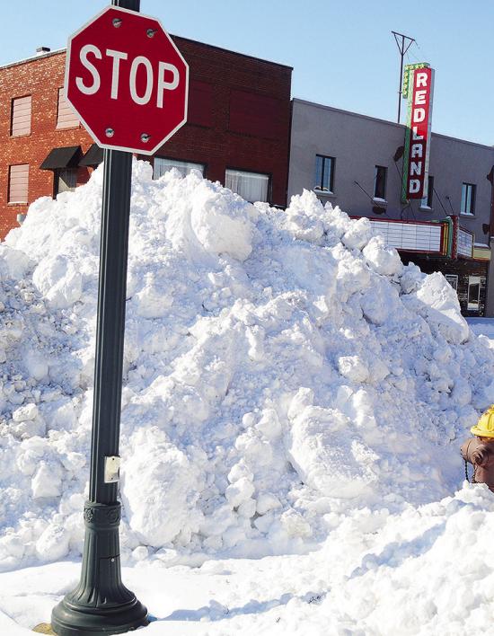 One of the many piles of snow plowed up as high as stop signs Monday morning after being cleared off the road at the intersection of Sixth Street and Frisco Avenue. CDN | Micah Ashcraft