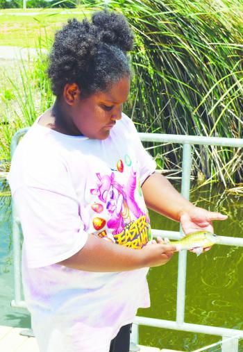 Jazzlyn Douglas shows off the fish she caught moments before at Acme Brick Park. CDN | Christian Jacobsen