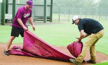 Rhett Blundell, left, and Lyndon Perry unroll a tarp to put on one of the fields at Schumacher Fields at Acme Brick Park Tuesday to protect it from the rain. CDN | Sam Goodwyn