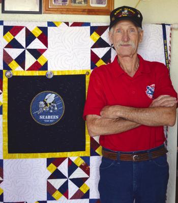 Mike Mapel stands in front of his Quilt of Valor, presented to him by the Cheyenne Senior Citizens Center, Monday at his home in Butler. CDN | Christian Jacobsen